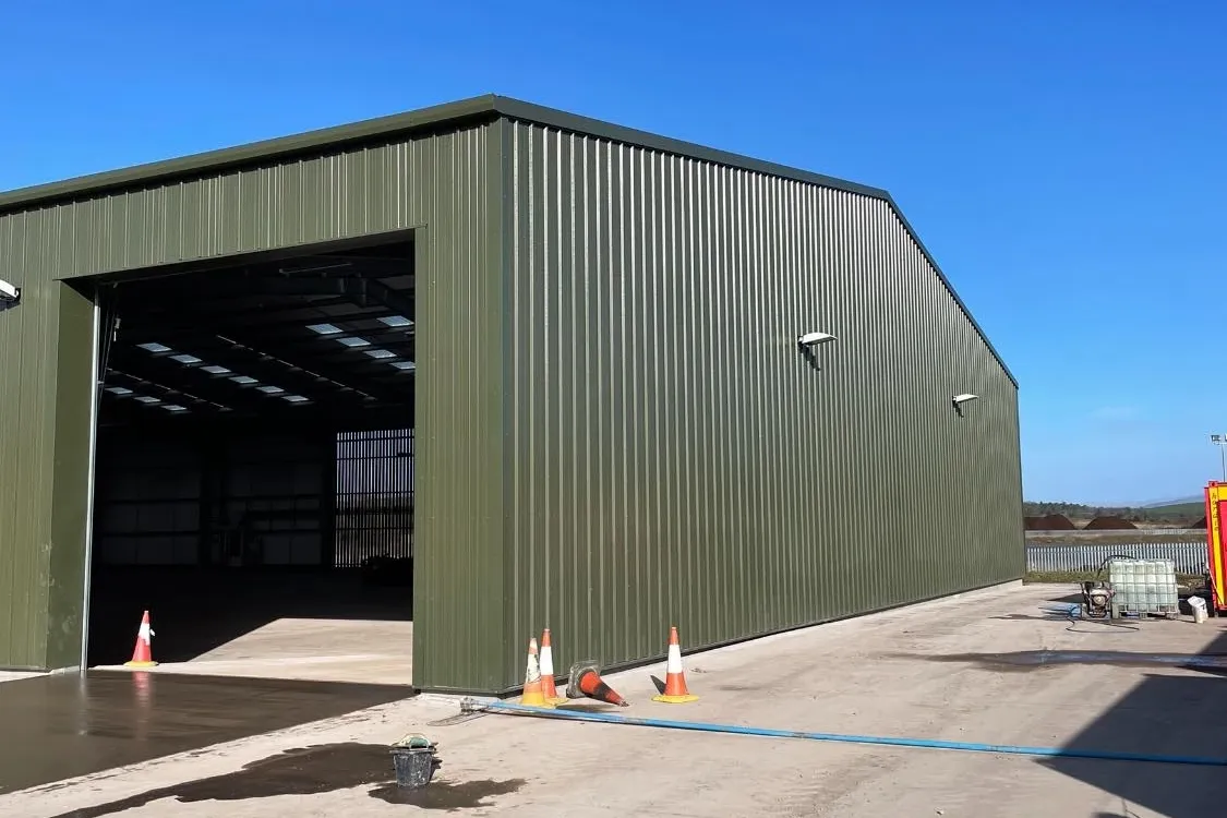 A large, newly constructed agricultural steel building in a field