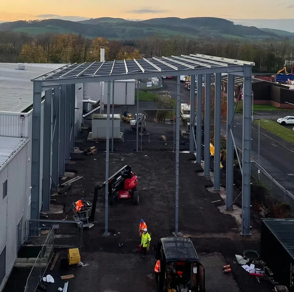 A large industrial steel warehouse under construction at dusk